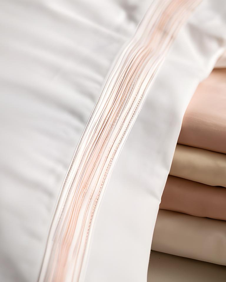 Close-up of a carefully finished pillowcase seam beside folded bedding